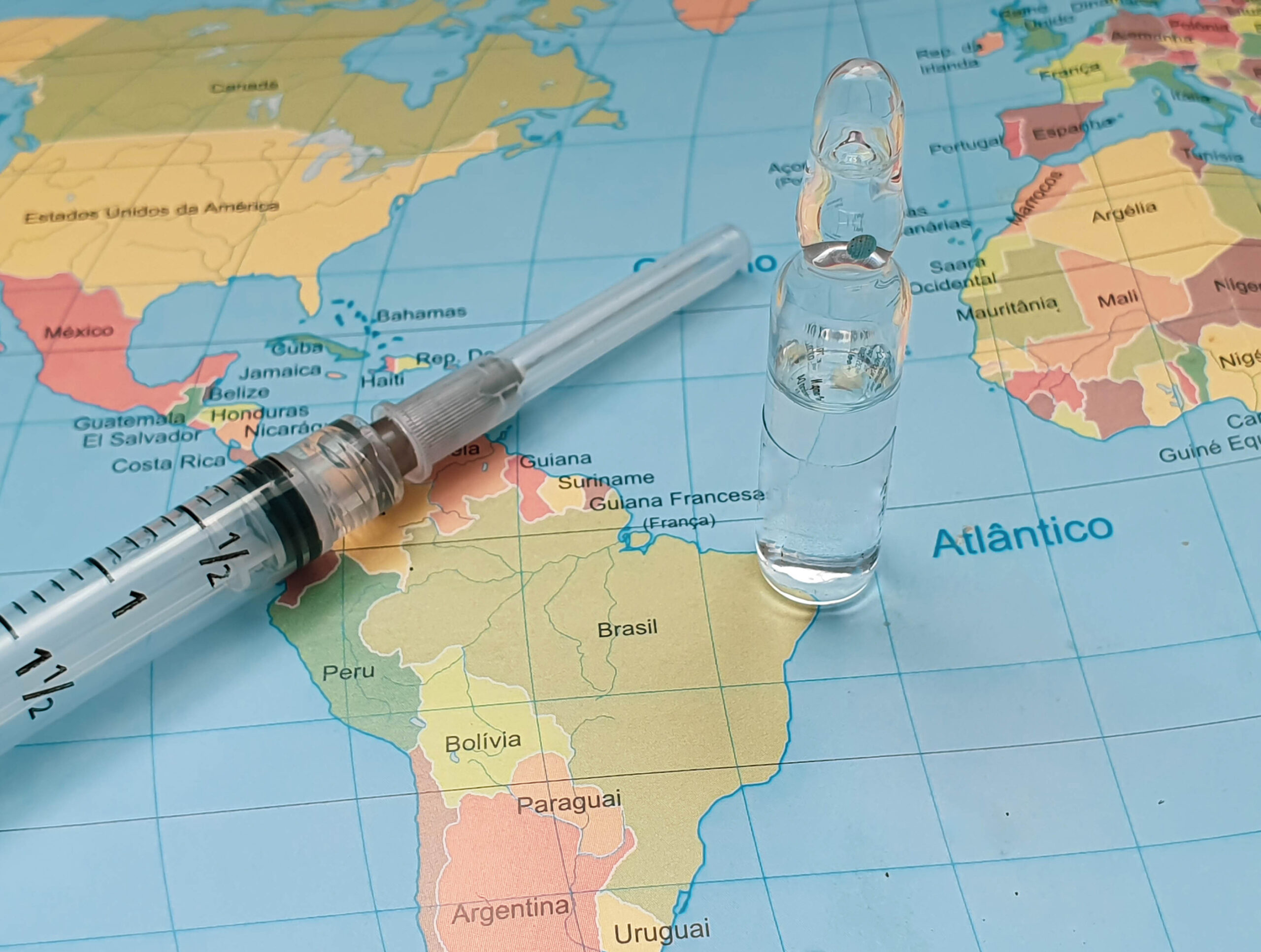 Syringe and vial on a map depicting mandatory travel vaccinations.