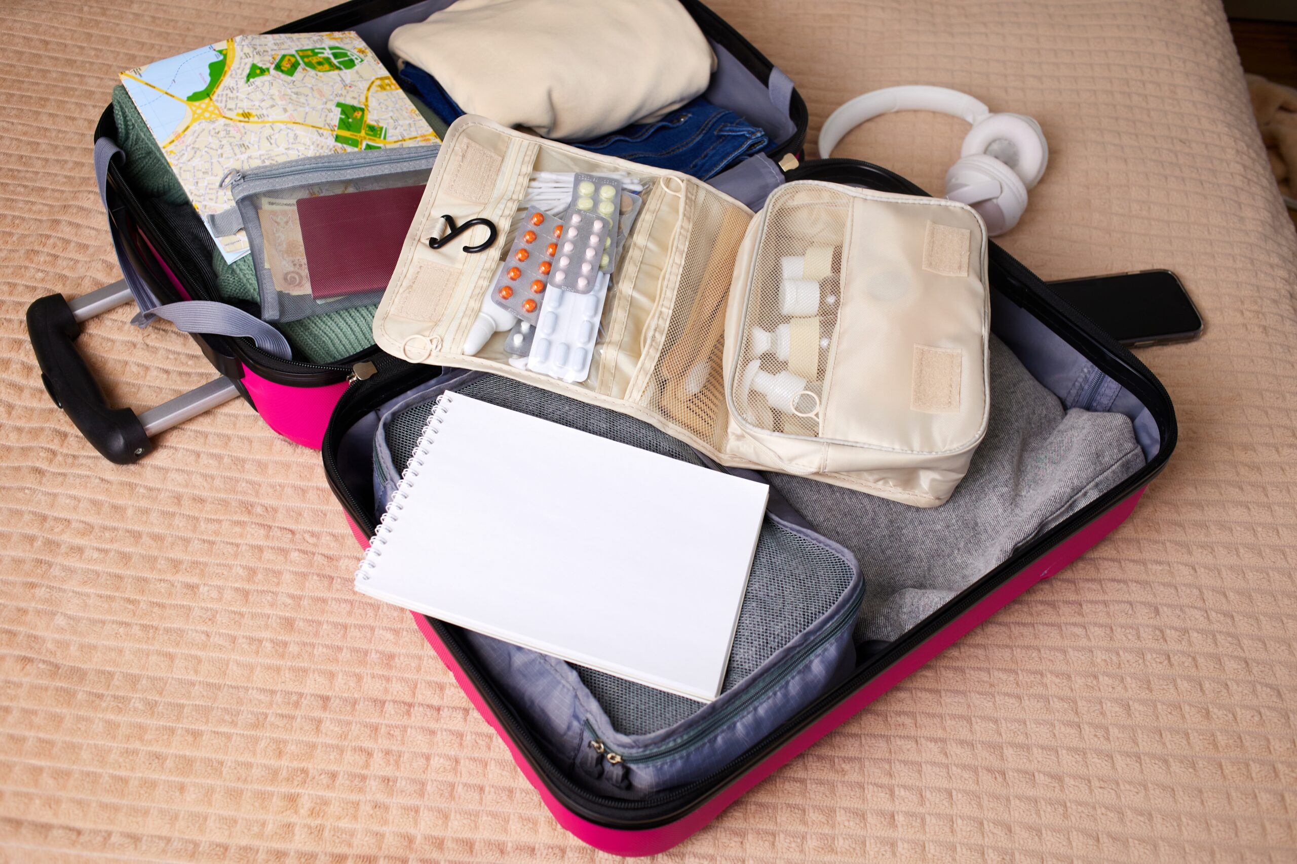 Open suitcase filled with clothing, medication and toiletries