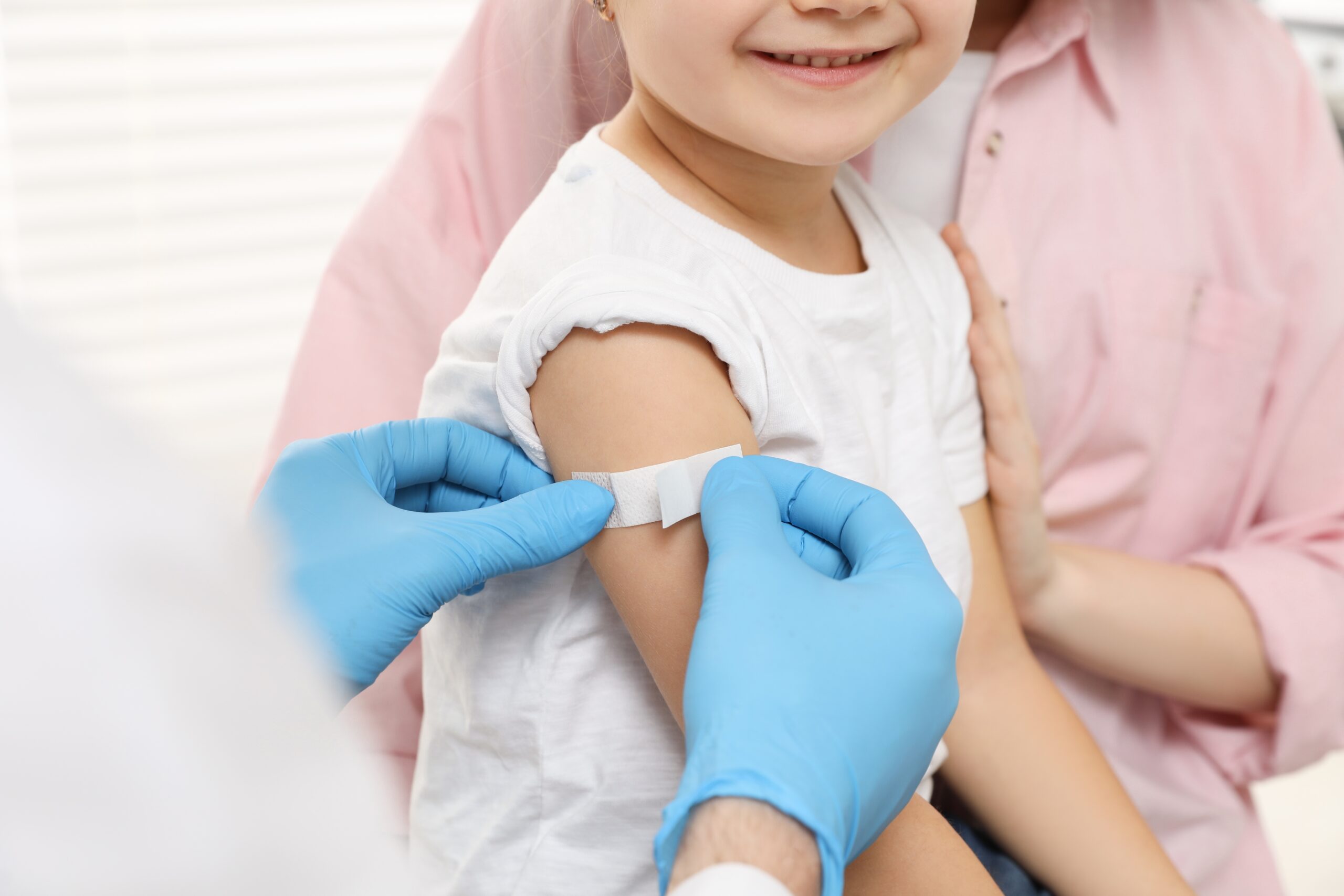Plaster being placed on child's arm after receiving vaccinations.