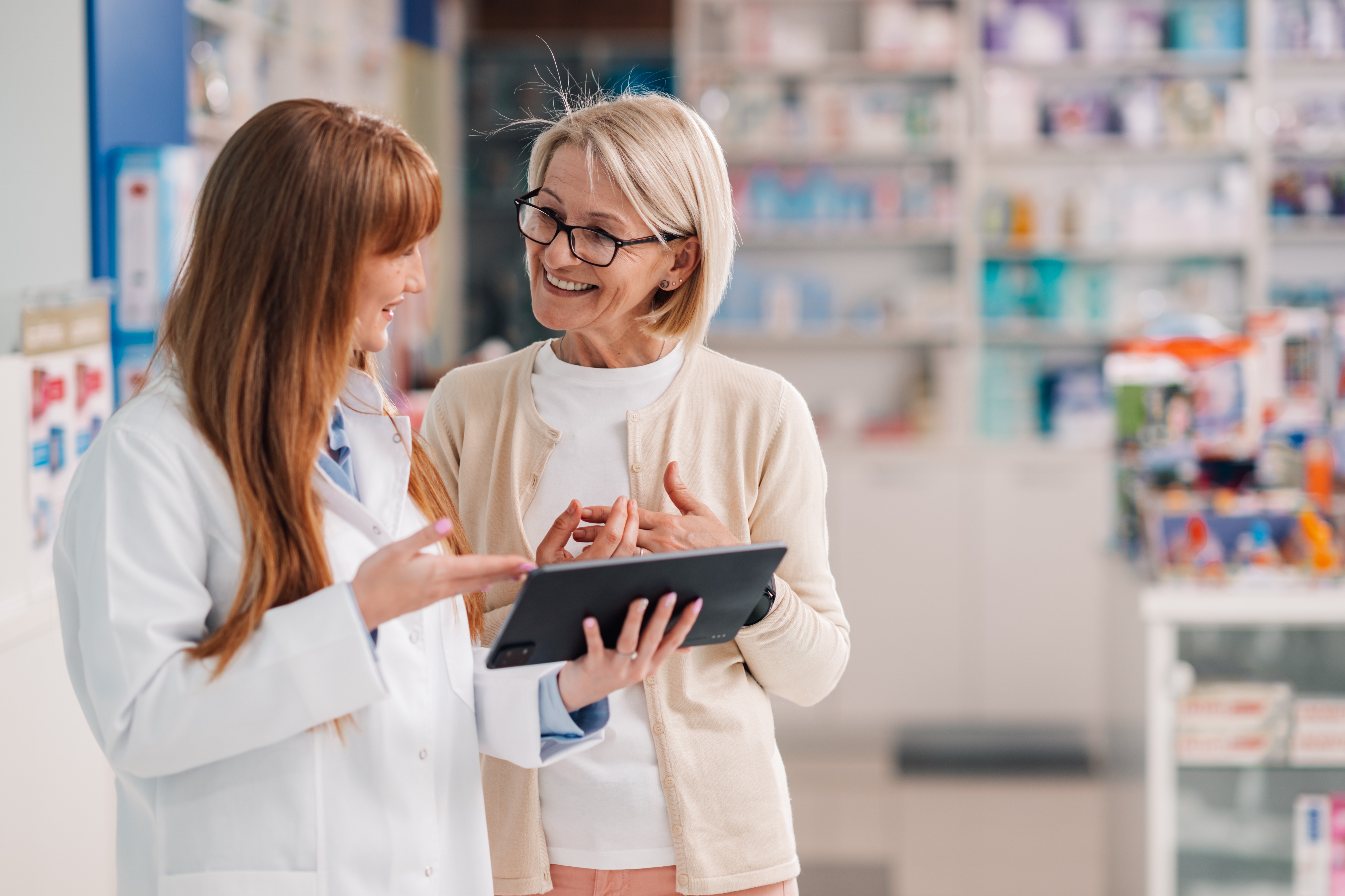 Pharmacist happily assists a customer in drugstore