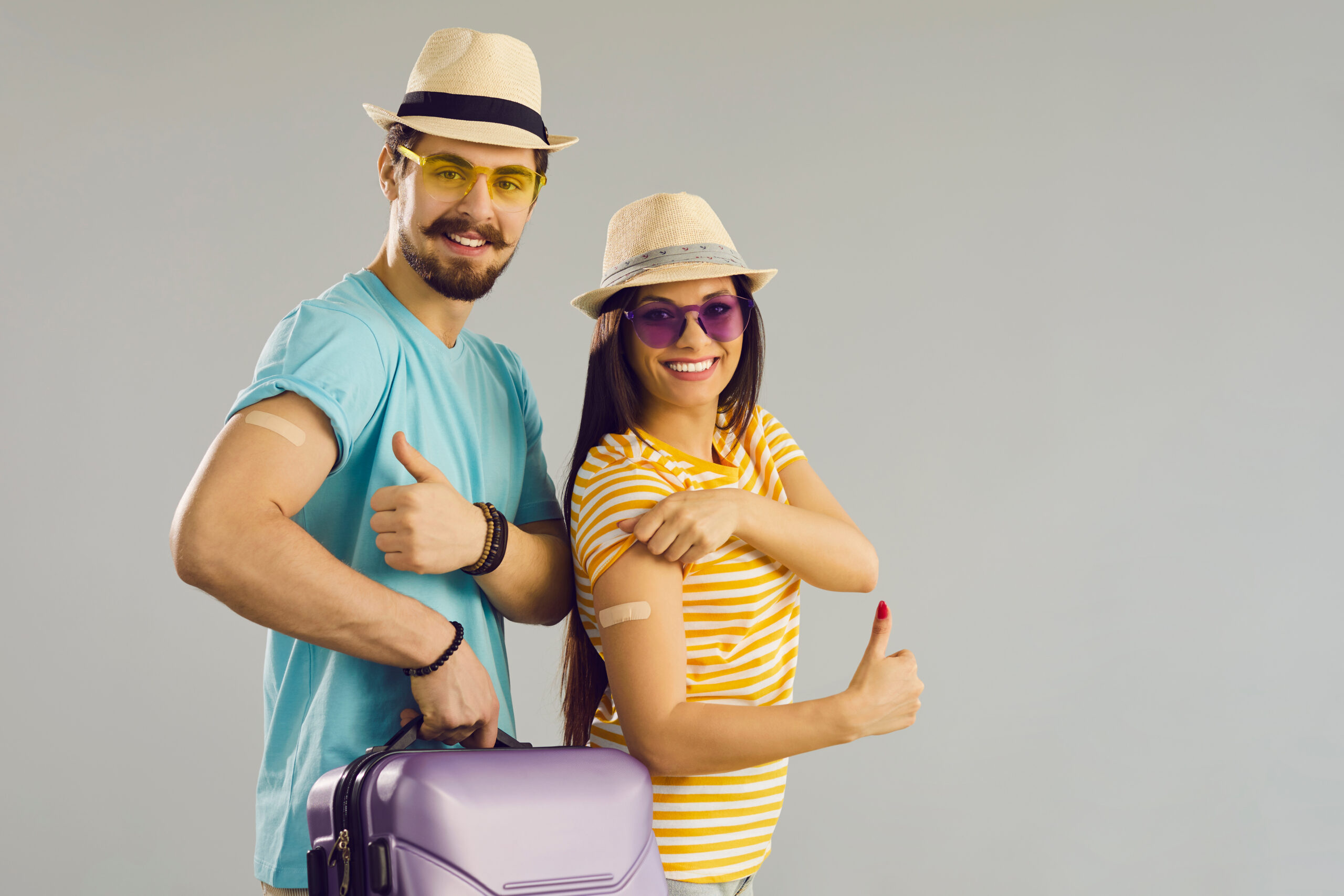 Happy smiling couple ready for safe travel giving thumbs-up sign after vaccination.