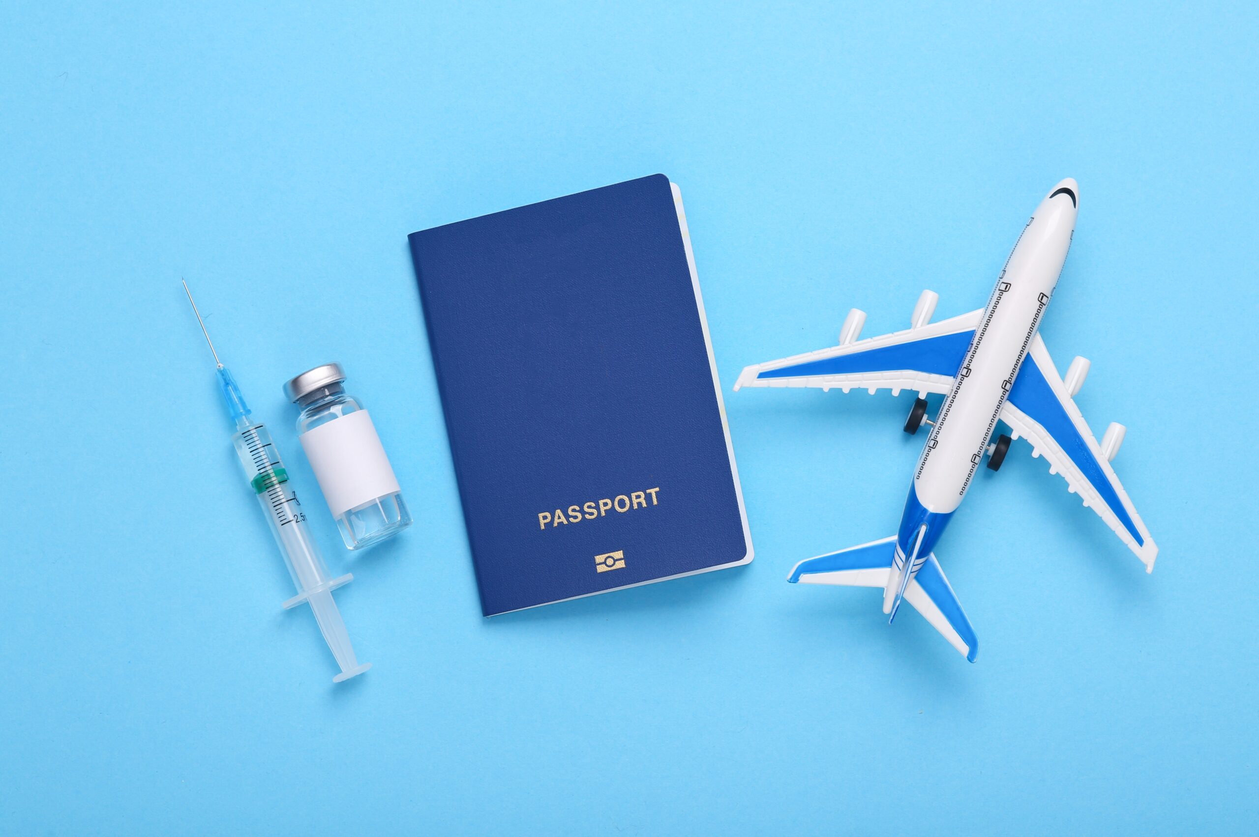 Airplane with a bottle of vaccine and a syringe, passport on a blue background