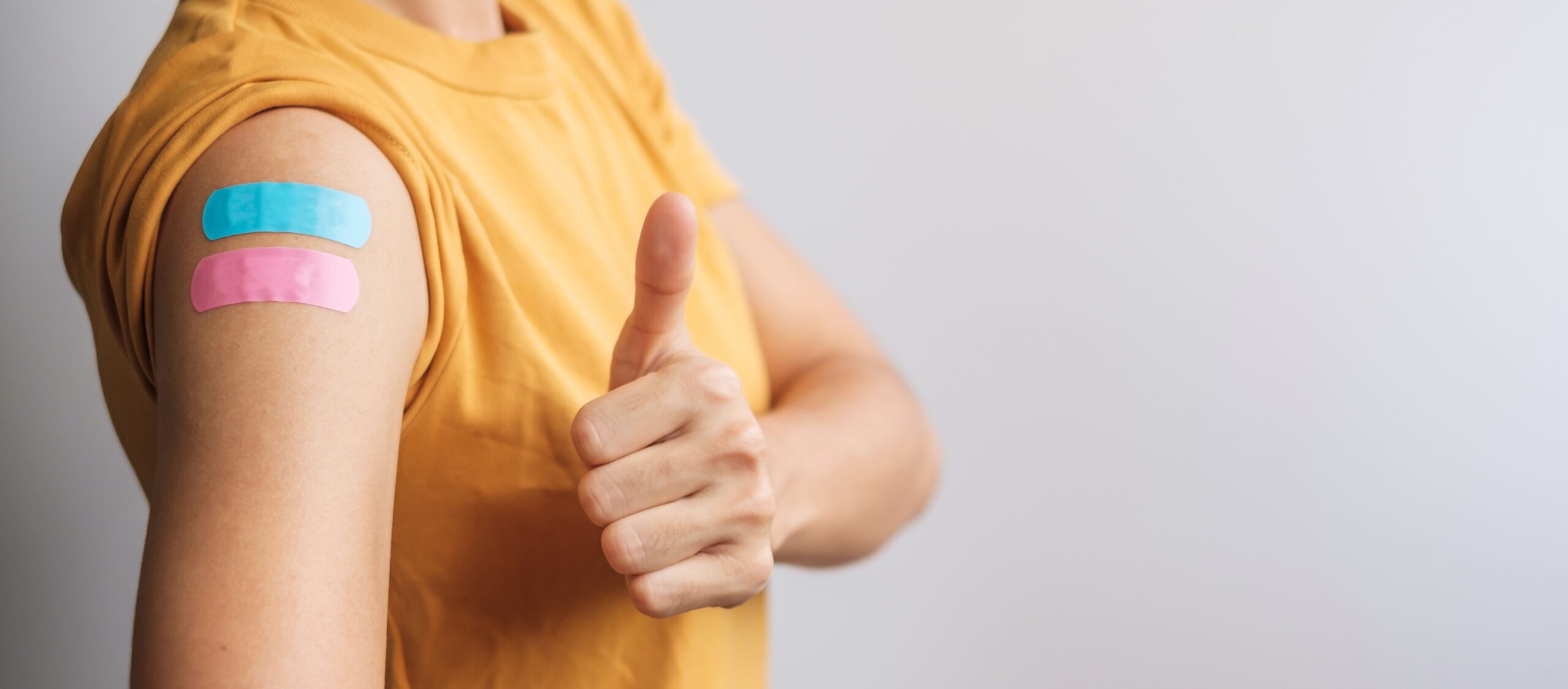 woman showing Thumb sign with bandage after receiving vaccine