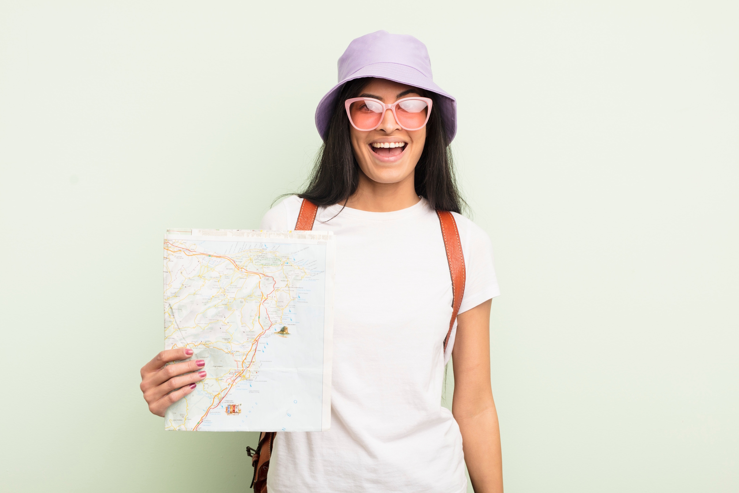 young female tourist wearing sunglasses and hat holding a map