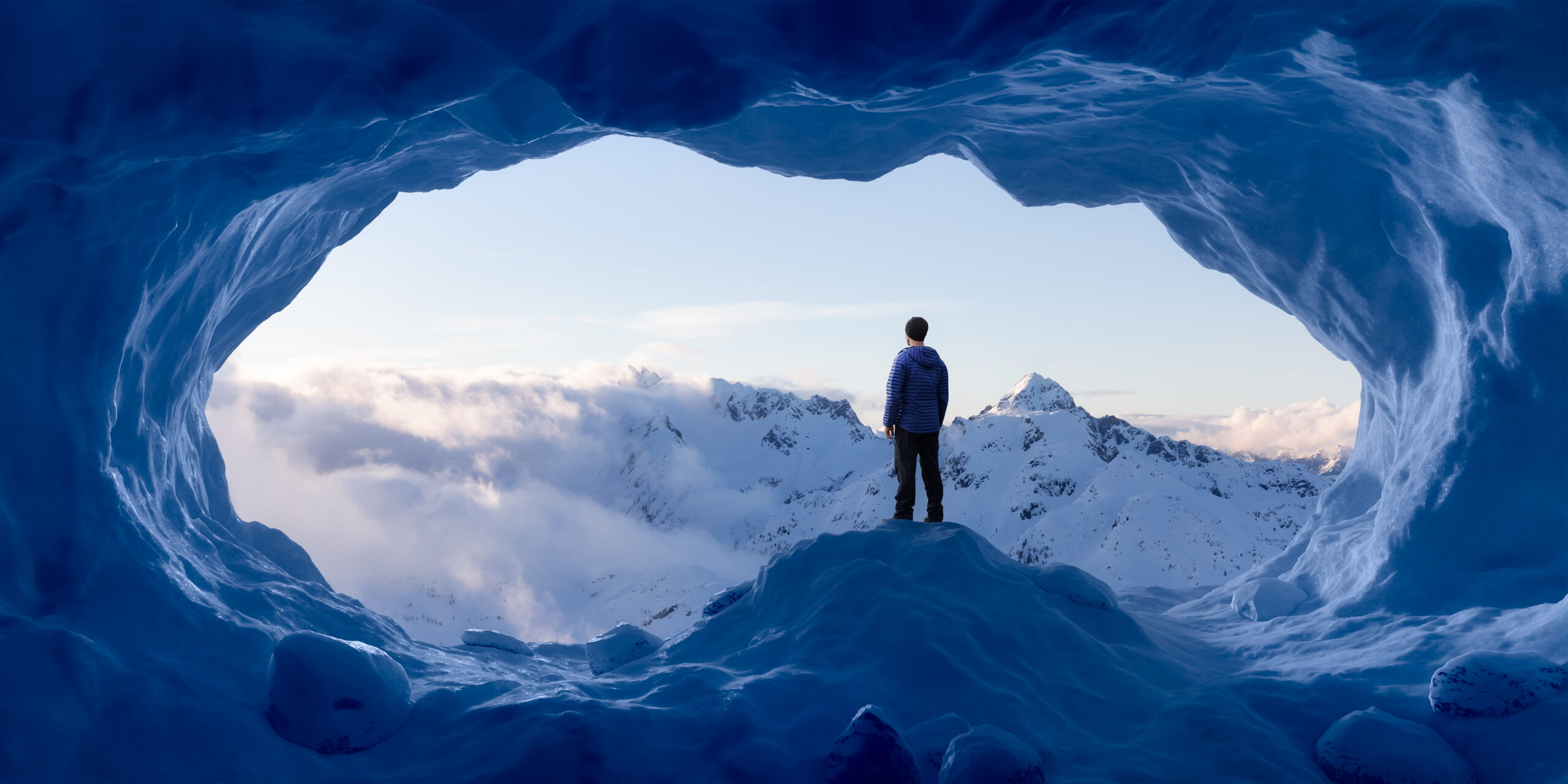 Adventurous Man Hiker standing in an Ice Cave with rocky mountains in background